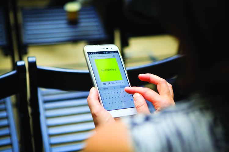 Person holding a smartphone typing a message on a digital sticky note